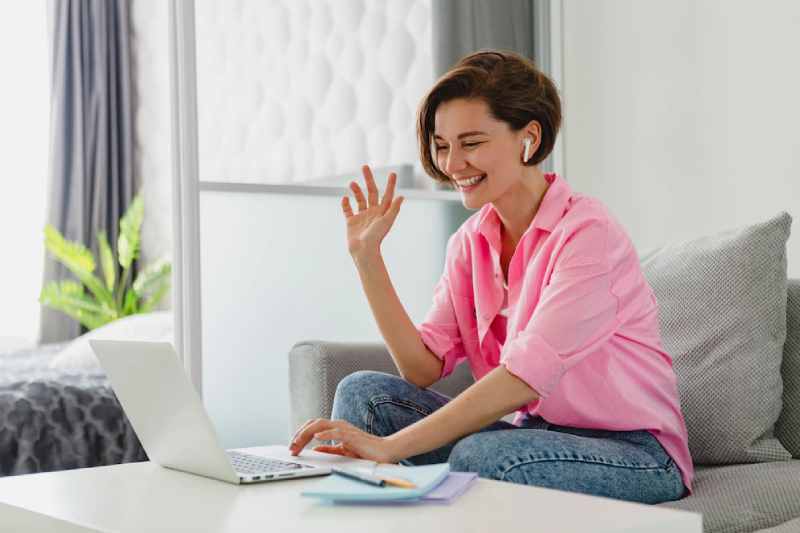 attractive smiling woman pink shirt sitting relaxed sofa home table working online laptop from home 285396 10075