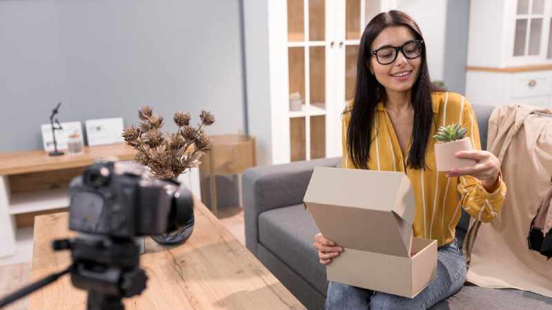 female vlogger home with camera unboxing plant 23 2148738205 1