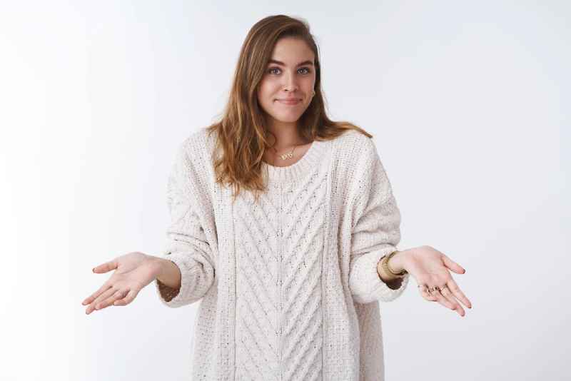 woman short hair loose cozy sweater shrugging hands sideways smiling awkward unaware 176420 44566